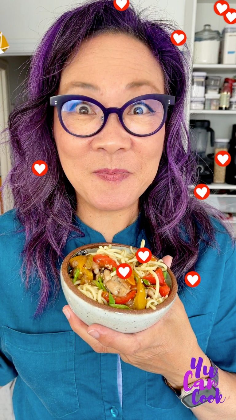 A person with purple hair and glasses holds a bowl of noodles and vegetables, smiling with an excited expression. Heart icons surround them, and a "You Can Cook" logo is in the corner. Kitchen appliances are visible in the background.